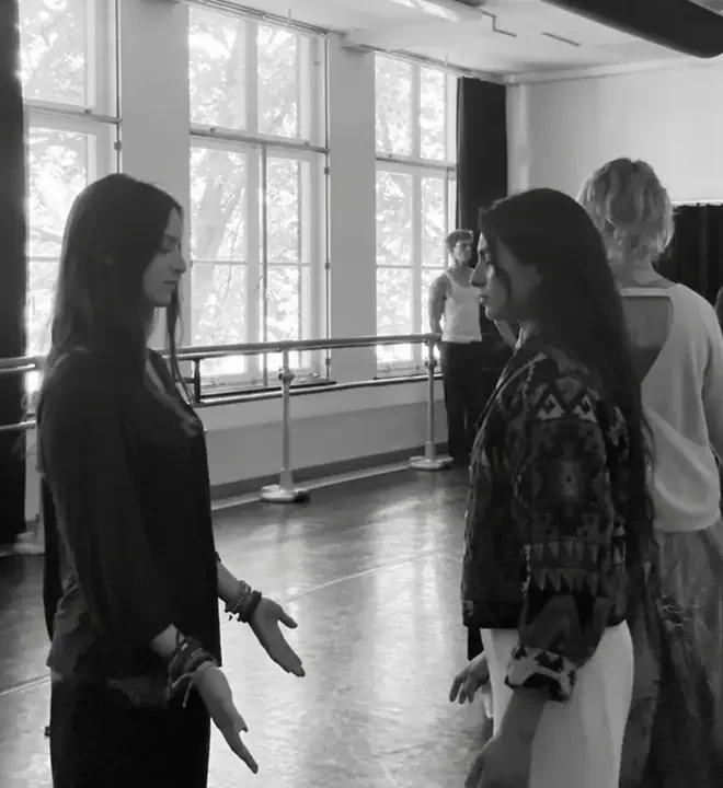 Two participants stand facing each other with their eyes closed in the studio